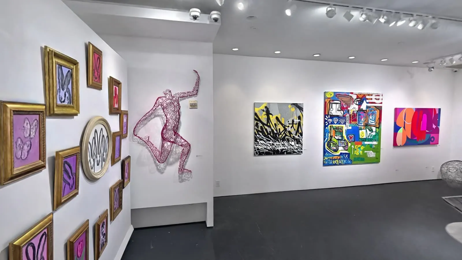 A salon-style wall and a wire figure