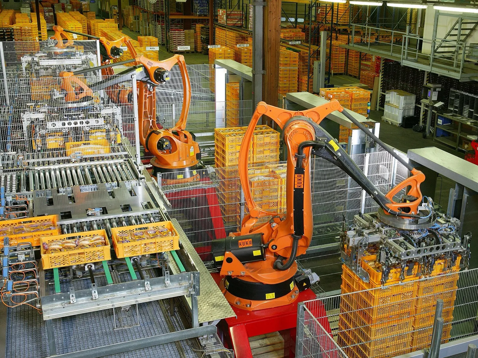 A palletizing cell with two robot arms, conveyors, guarding and a building column