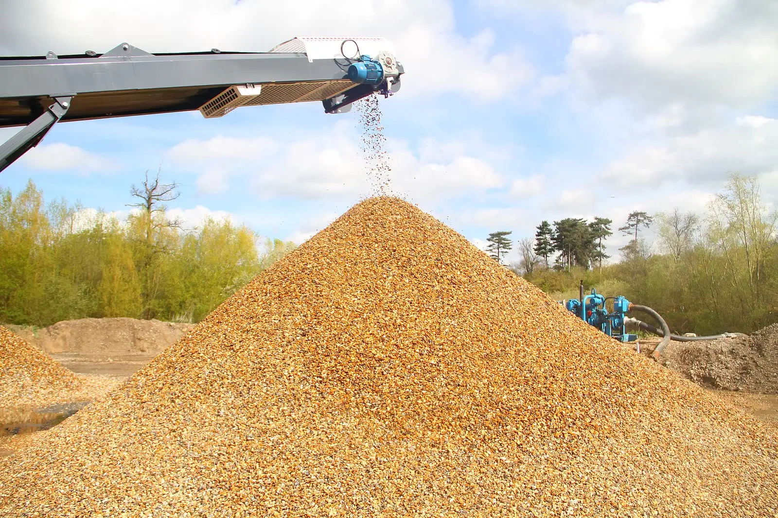 A conveyor building a cone-shaped stockpile of gravel at an aggregate plant