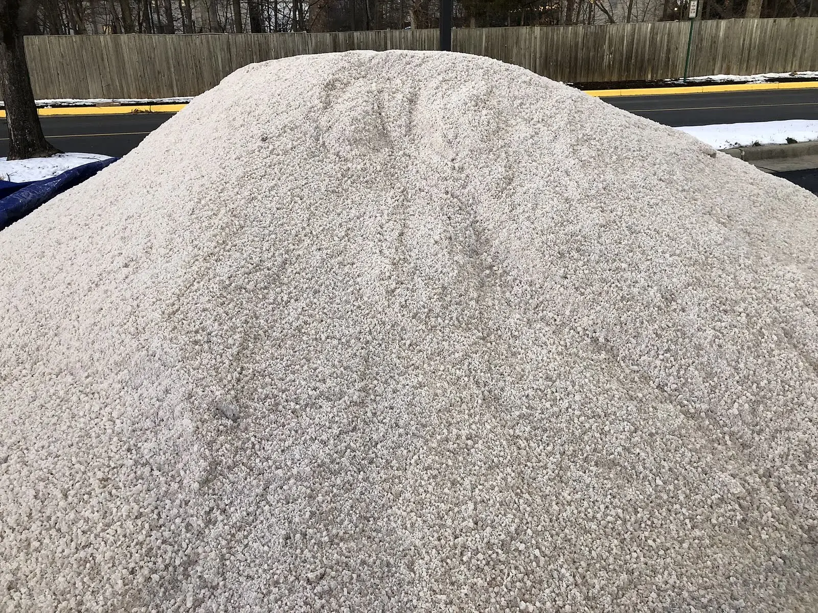 A pile of road salt beside a road after a snowfall