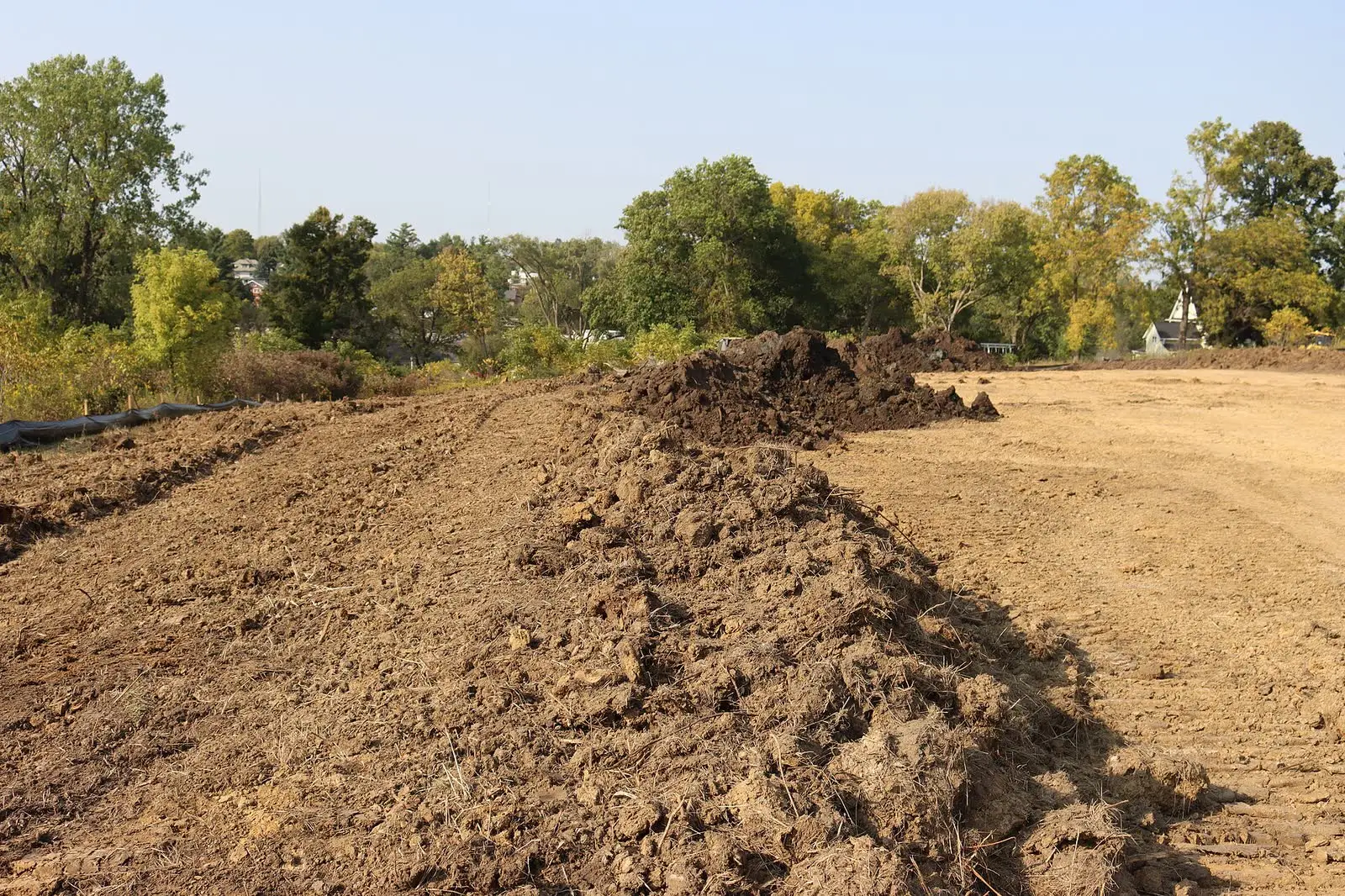 A bulldozer shaping a berm of excavated soil on a construction site